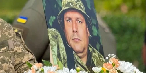 Портрет захисника в камуфляжі серед білих квітів на церемонії прощання